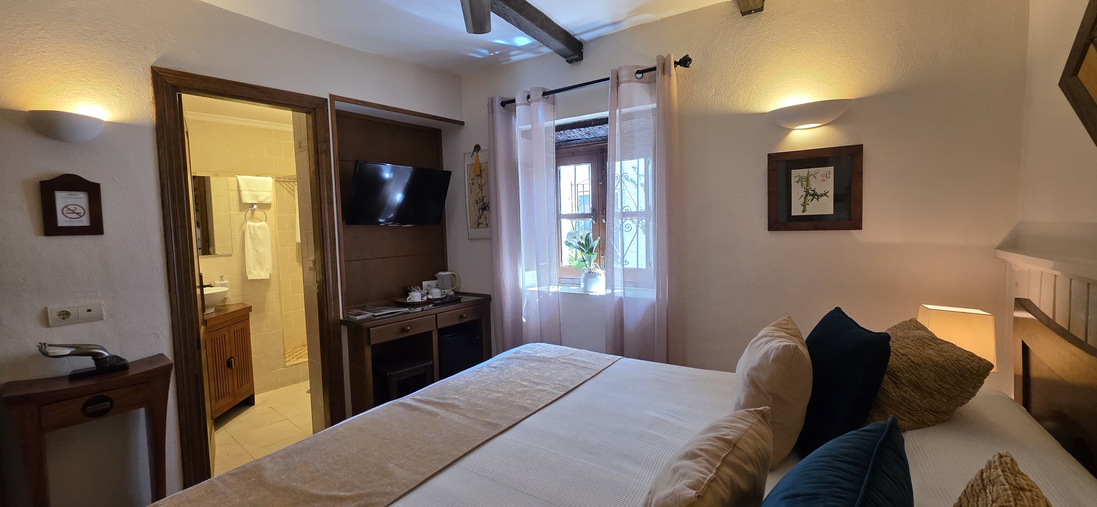 A guest room at La Villa Marbella with linen curtains and a hand-carved wooden sideboard