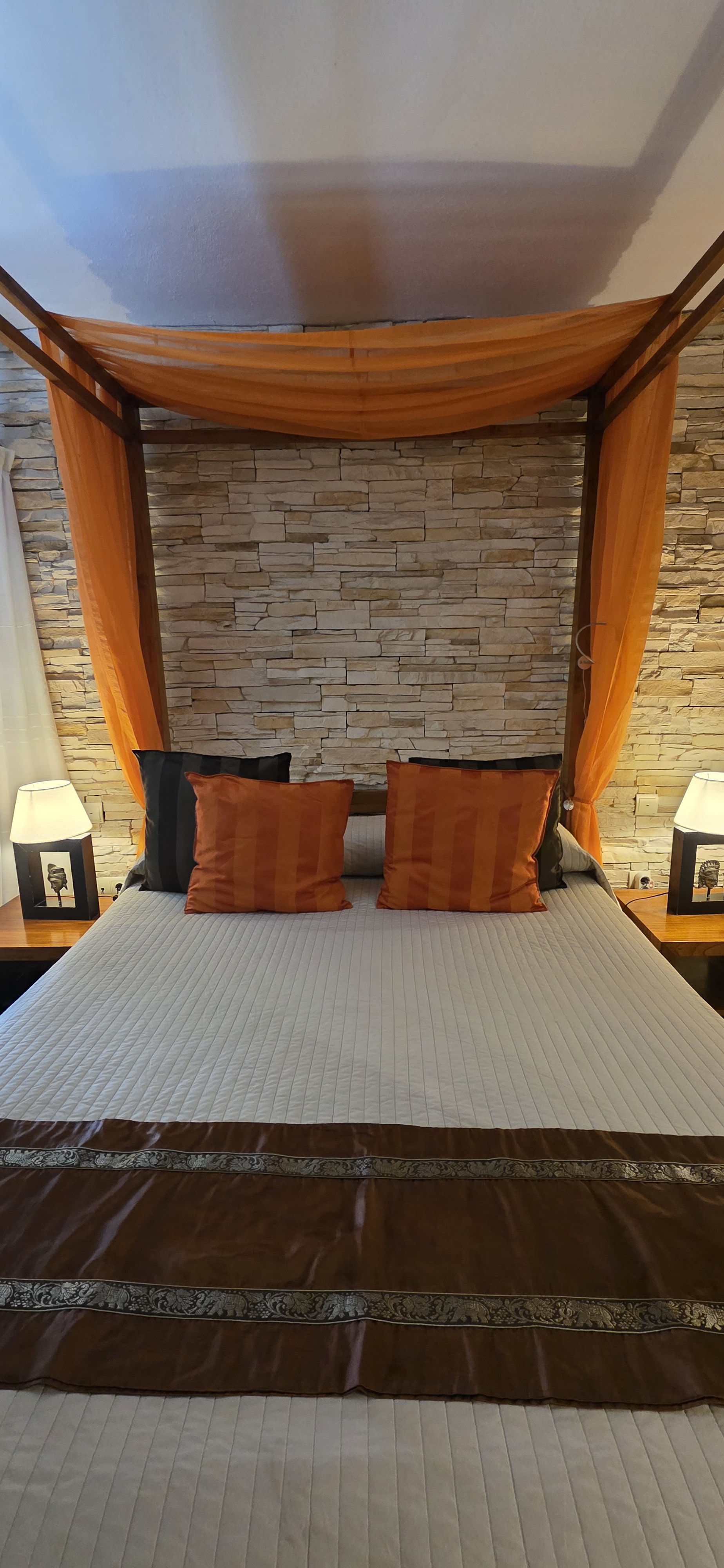 Brass plates and a woven textile hanging on a whitewashed wall above a guest bed at La Villa Marbella