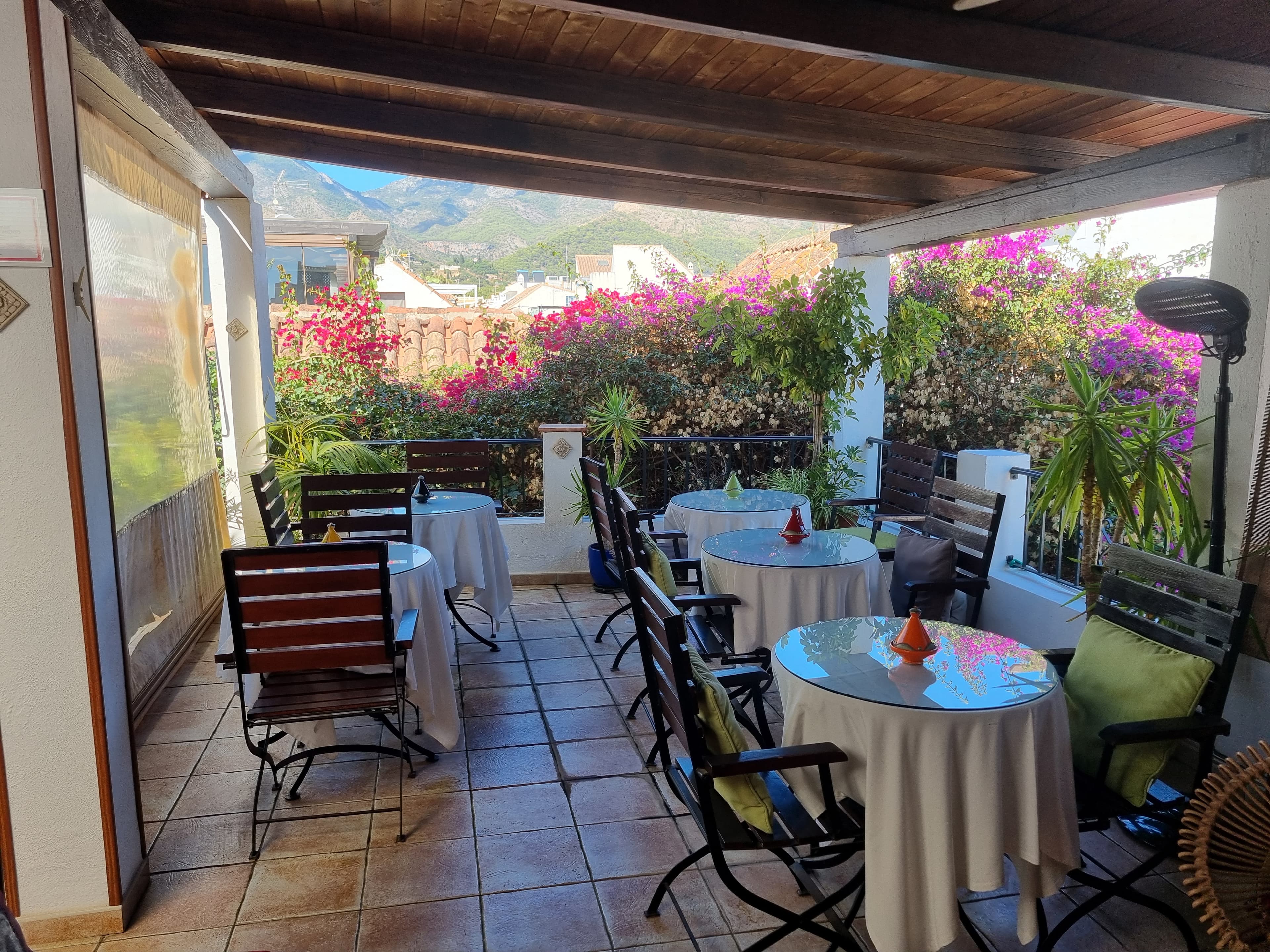 Covered terrace at La Villa Marbella with breakfast tables, bougainvillea, and the Sierra Blanca beyond